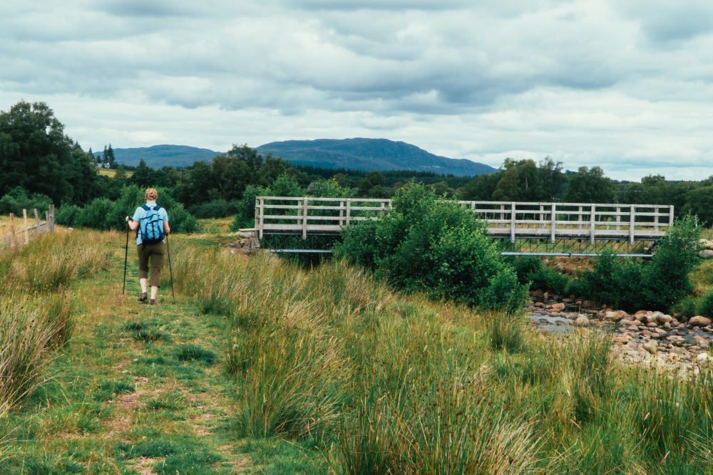 Walker crossing a bridge on the South Loch Ness Trail near Whitebridge